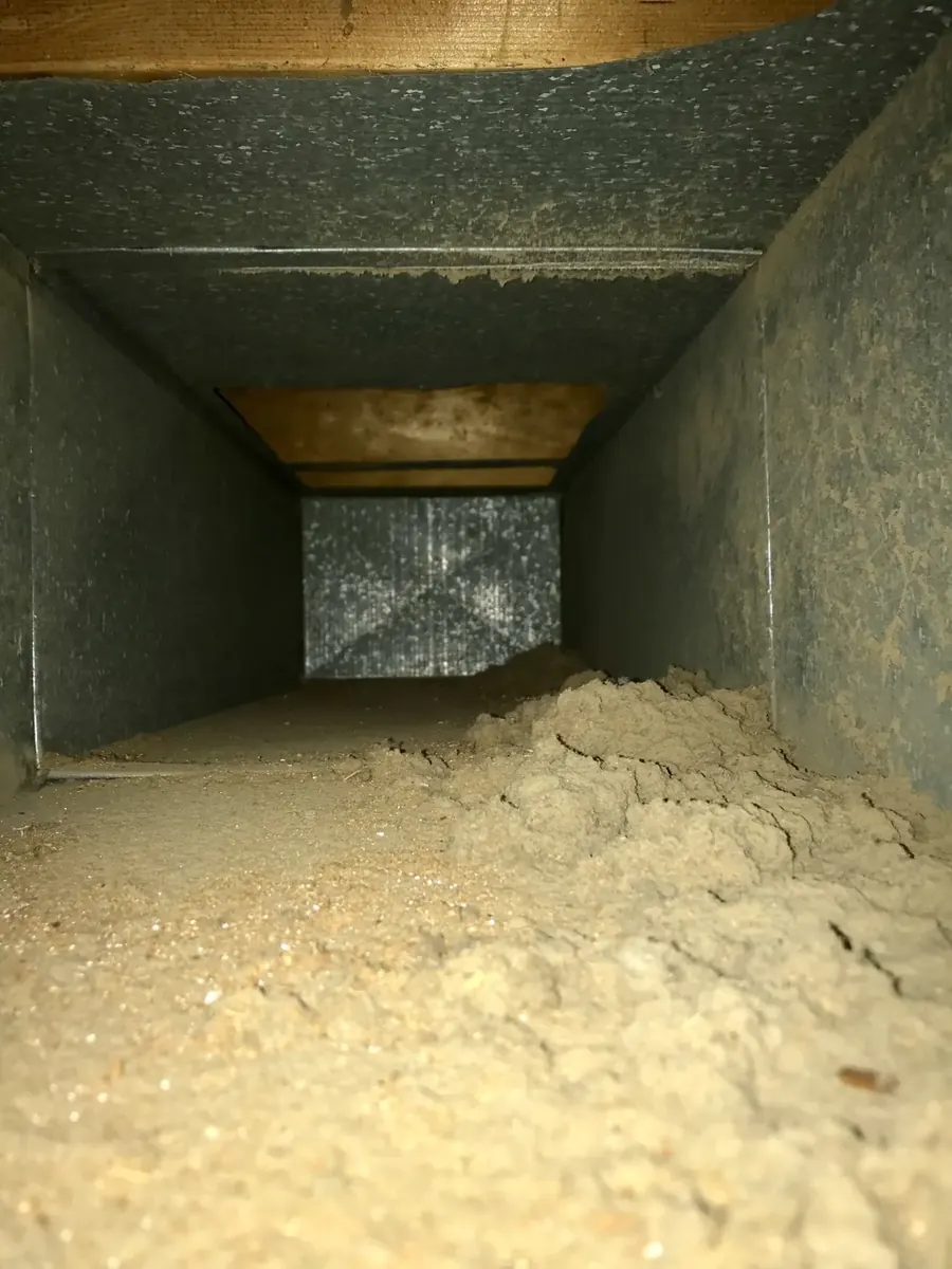 Inside of a home air duct before Vortex cleaning, coated with thick dust and pet dander