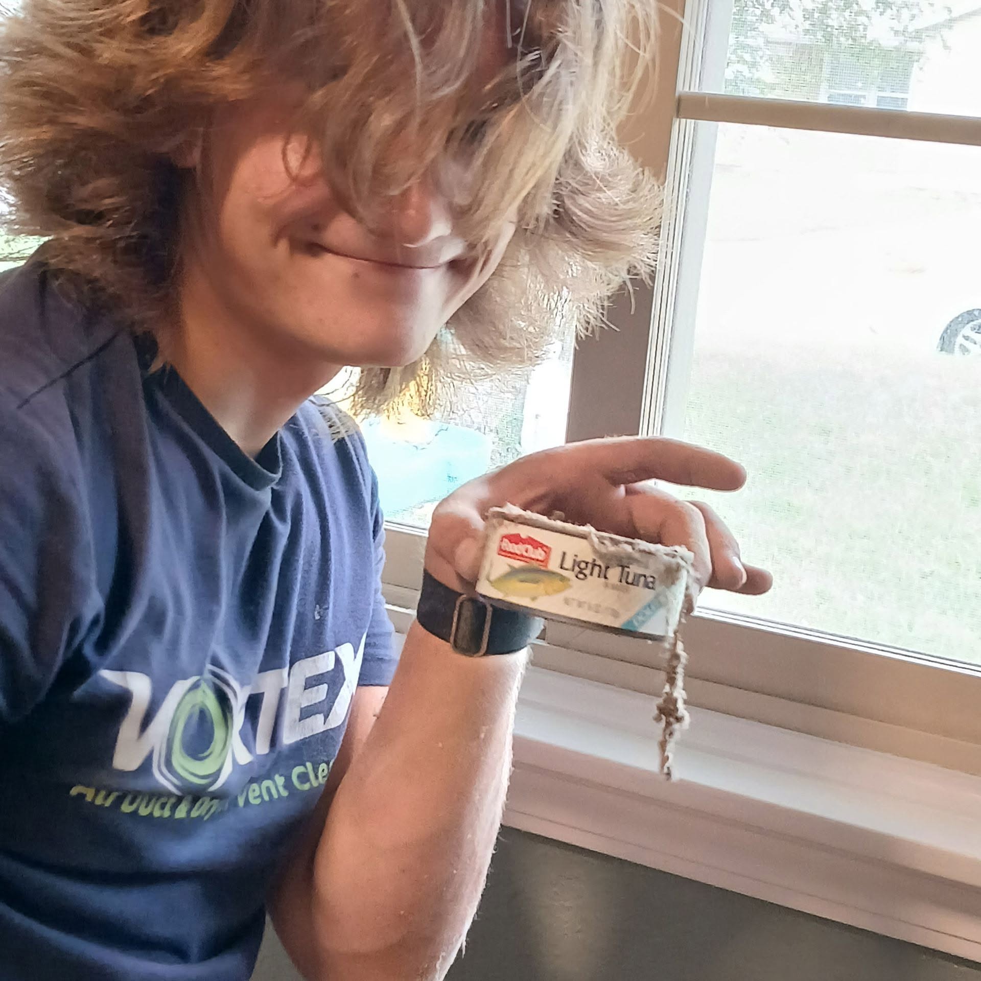Vortex technician holding a dusty can of light tuna recovered from inside a home's air duct system